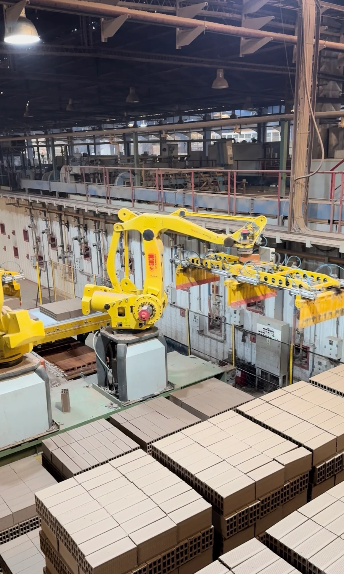 Brazo de robot industrial y ladrillos en una línea de producción