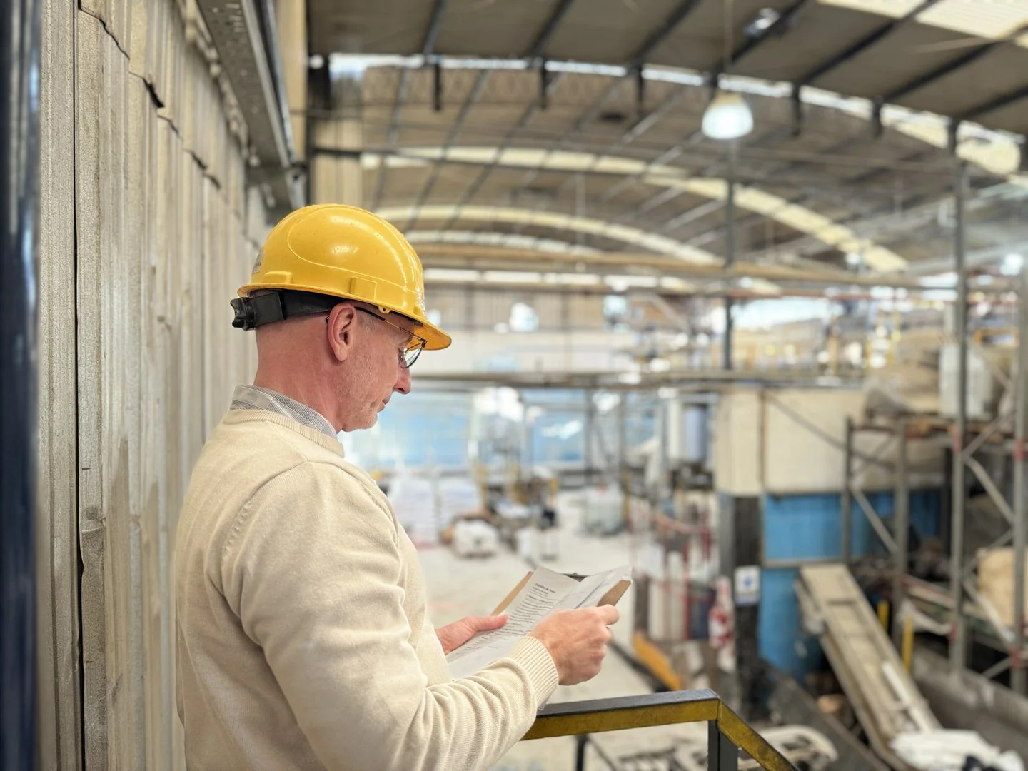 Asesor de ATENDER revisando un relevamiento con la nave industrial de fondo